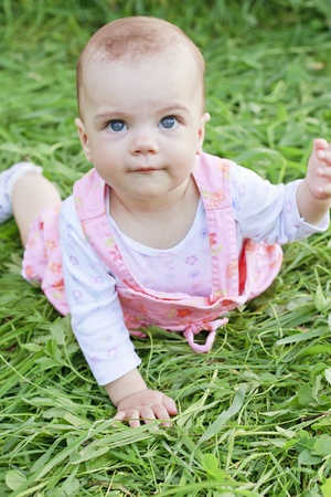 Happy baby girl lying on grassの写真素材