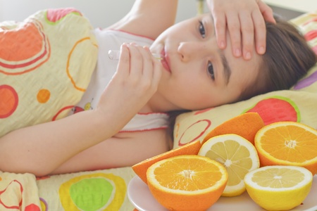 Sick little 7 years old girl with a thermometer in bedの写真素材