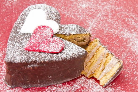 Heart shaped slice of a chocolate-cake on red  plateの写真素材