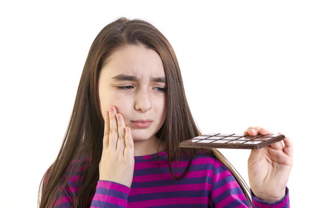 Girl child with toothache because his eats chocolateの写真素材