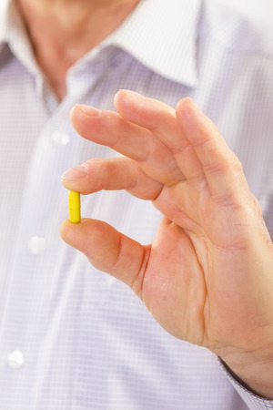 Senior adult man holds medicine capsule in his handの写真素材