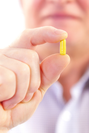 Senior adult man holds medicine capsule in his handの写真素材