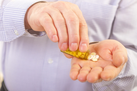 Senior adult man holds medicine capsule in his handの写真素材