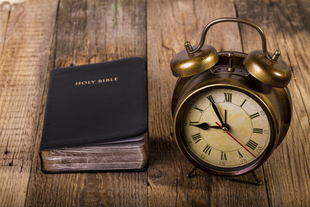 Holly Bible with clock on wood. Focus on clock.の写真素材