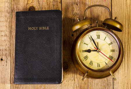 Holly Bible with clock on woodの写真素材