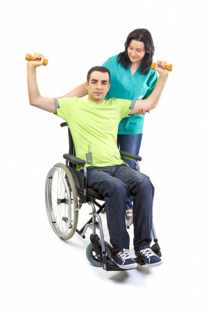 Physical therapist works with patient in lifting hands weights. Young adult in wheelchair.の写真素材