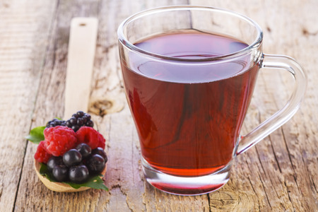 Fruit red tea with wild berries in wooden spoon on brown wooden tableの写真素材