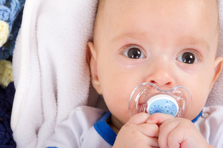cute baby with a nipple looking at camera