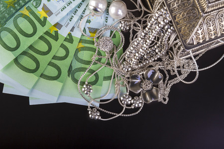 Silver jewelry and euro on black background.の写真素材