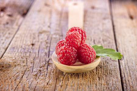 fresh berries in wooden spoon on wooden tableの写真素材