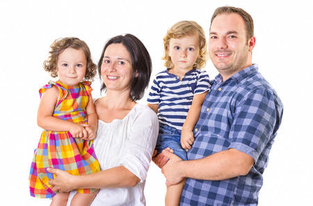Happy family of four smiling while standing against white background.の写真素材