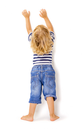 Back view of little boy with hands up on white backgroundの写真素材