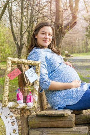 Beautiful pregnant woman outdoor in the park on benchの写真素材
