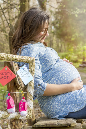 Beautiful pregnant woman outdoor in the park on benchの写真素材