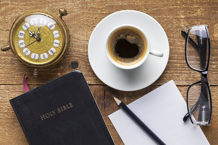 Holy Bible, alarm clock, glasses and coffee on wood table. Studying  the Bible concept. Focus on the Bibleの写真素材