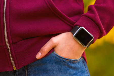 Young girl wears smart watch with hand in pocket. Focus on smart watch!