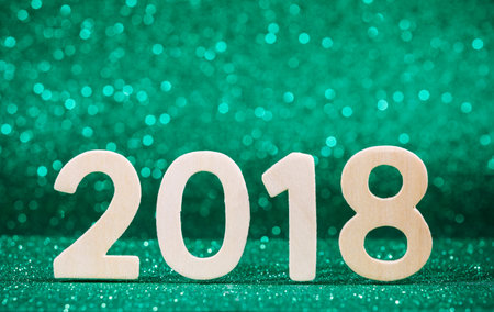New year 2018 white wood number on green paper with glitter lights