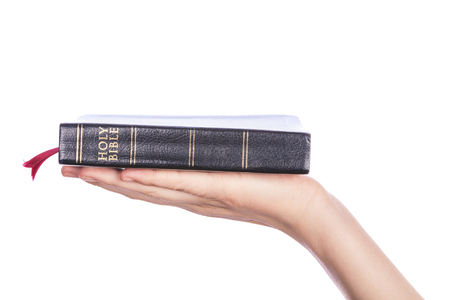 Woman hand holding the Holy Bible on white background. Focus on text.の写真素材