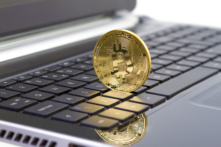 Golden bitcoin digital currency on laptop keyboard. Cryptocurrency a form of electronic cash.の写真素材