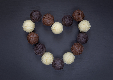 Chocolate truffles assortment heart shape on black stone.の写真素材