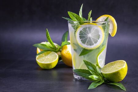 Cold refreshing summer lemonade with mint in a glass on a grey and black background. Focus on glass.の写真素材