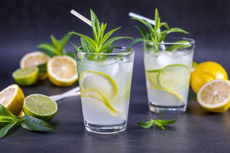 Cold refreshing summer lemonade with mint in a glass on a grey and black background. Focus on glass.の写真素材