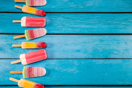 Colorful fruit ice cream stick look fresh to eat placed on a blue vintage wooden. Focus on ice crean...
