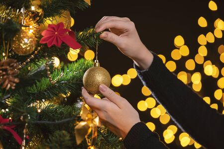 Girl decorates a Christmas tree. Closeup image of female hands decorating Christmas tree.の写真素材