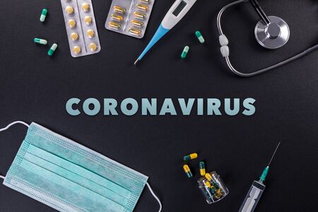 Protective masks, medicines, thermometer, stethoscope and syringe with coronavirus text on a black background. Novel coronavirus 2019-nCoV, MERS-Cov middle East respiratory syndrome coronavirus.の写真素材
