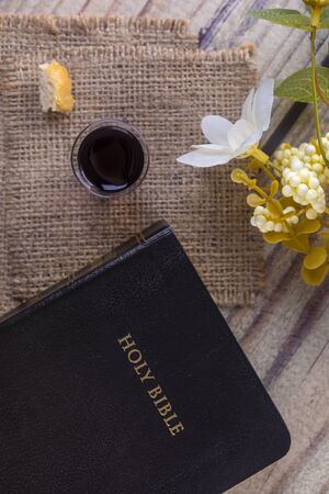 Taking communion concept - the wine and the bread symbols of Jesus Christ blood and body with Holy Bible. Easter Passover and Lord Supper concept Focus on glass.の写真素材