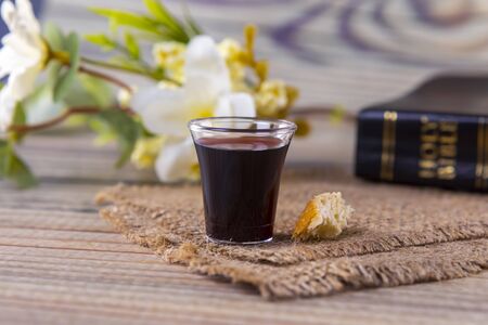 Taking communion concept - the wine and the bread symbols of Jesus Christ blood and body with Holy Bible. Easter Passover and Lord Supper concept Focus on glass.の写真素材