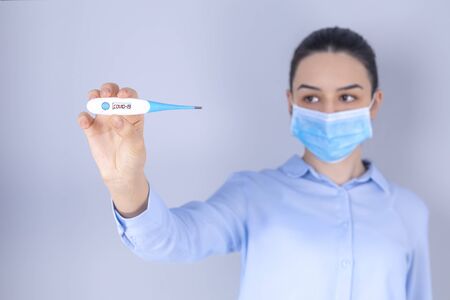 COVID-19 Pandemic Coronavirus Mask Fever Worry Girl Checking Temperature with Thermometer at Home Symptom of SARS-CoV-2. Girl with mask on face check fever one of symptoms of Coronavirus Disease 2019の写真素材