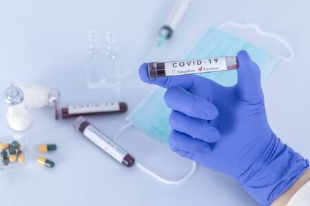 Analyst hand with protective gloves holding COVID 19 Coronavirus test blood. Virus test and research concept. Focus on test blood.の写真素材