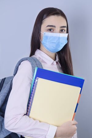 High school girl with mask on her face going back to school. Student girl ready for school during the coronavirus pandemic. Focus on her face.の写真素材