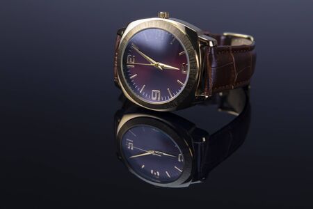 Men watch with leather bracelet on black glossy background. Focus on 9 a clock number.の写真素材
