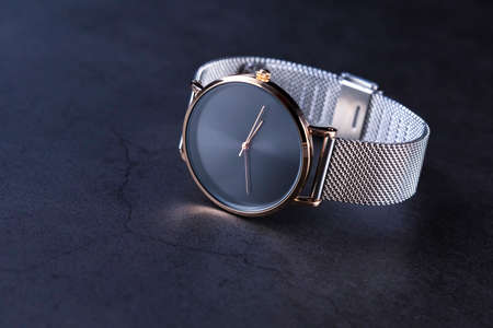 Black wrist watch for women with metal strap top view on gray background. Focus on the those of clock.の写真素材