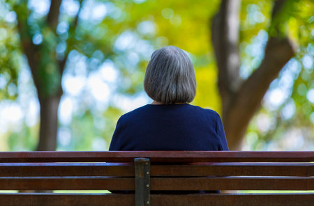 Aged woman sitting on bench in autumn park.の写真素材