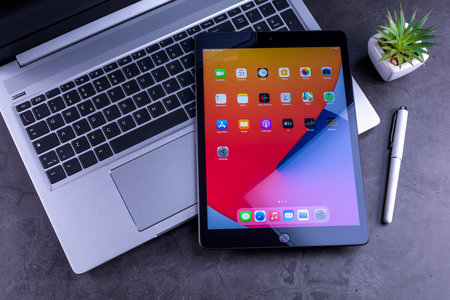 Galati, Romania, March 31, 2021: - Apple release new iPad 8th generation with the powerful A12Â BionicÂ chip, support for AppleÂ Pencil and the SmartÂ Keyboard. iPad 8th generation over silver laptop on desktop.のeditorial素材
