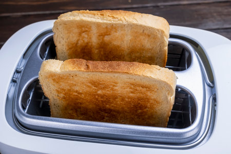 Slices of great toast coming out of the toaster. Healthy breakfast food and heating technology concept.の写真素材