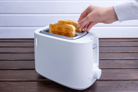 Slices of great toast coming out of the toaster. Healthy breakfast food and heating technology concept.の写真素材