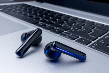 Black wireless headphones over laptop on table backgroundの写真素材