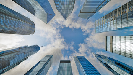 Clouds on blue sky passing over skyscrapers business buildings in the morningの写真素材