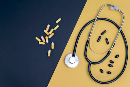 Stethoscope and pills on a black and yellow background, top viewの写真素材