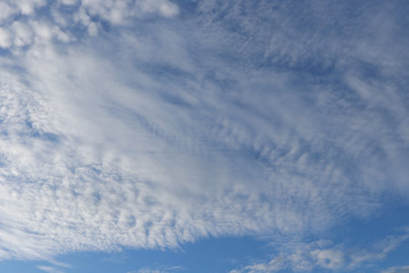 White altocumulus clouds and blue sky background.