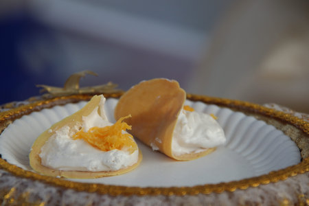 Two Thai crispy crepe are on white plate. Top of crispy crepe are white cream and golden threads...