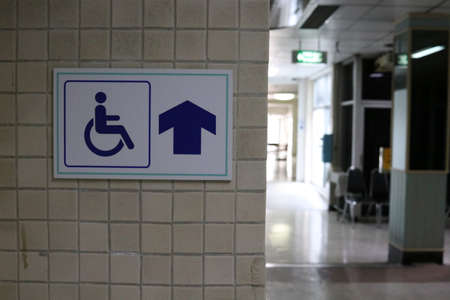 Sign wheelchair way is on light brown wall in building.の写真素材
