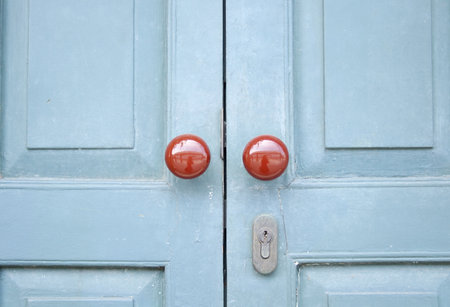 Red brown round shape door knob on painted light blue wood door closed.の写真素材