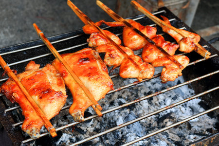 Chicken in bamboo clamp roasting on retro charcoal stove, street food in Thailand.の写真素材