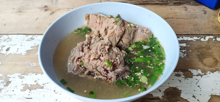 Pork backbone sour soup or Tom leng in light blue bowl on old wood table, Thailand. Use spine bone...