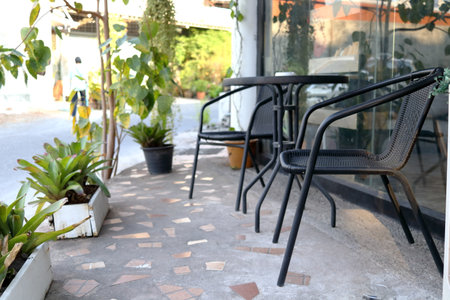 Black color set of metal chair and table on concrete floor outside coffee shop, white pot and plant decor beside, Thailand.の写真素材
